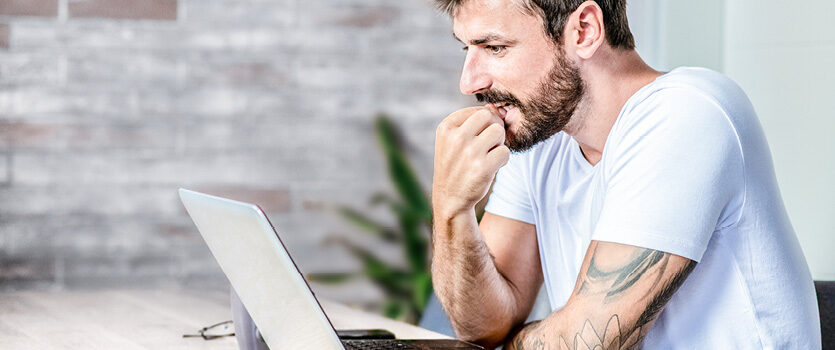 Unsicherer Mann vor seinem Laptop